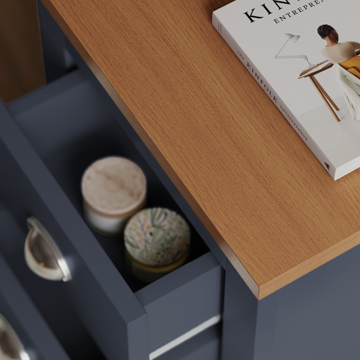 [Blue] Close framing of blue bedside table pair drawer pulled out, two small pots inside, oak top with book in upper corner