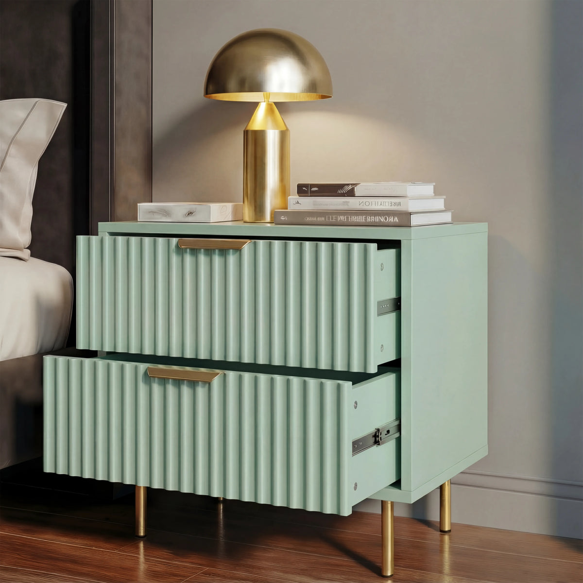 [Sage Green] nightstand with gold legs and handles beside a bed, displaying two drawers partially open in soft natural lighting