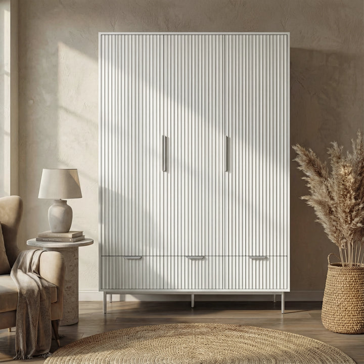 [White] flutrina design triple wardrobe with three drawers and silver legs placed against a wall in a natural light room