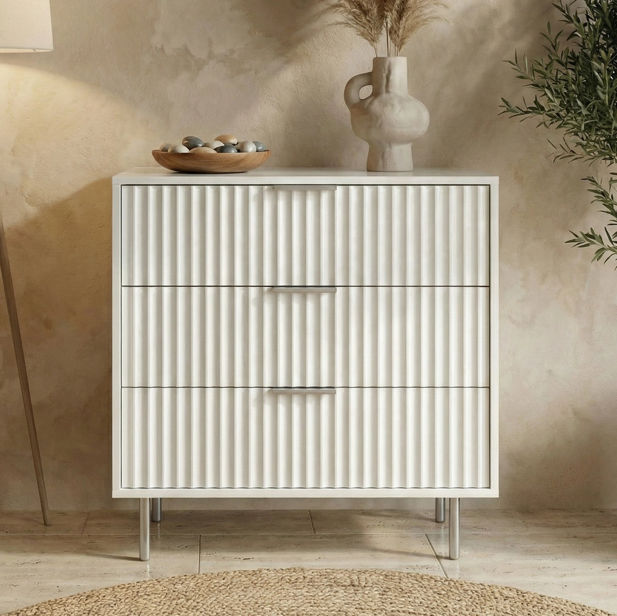 [White] 3 chest of drawers compact storage unit with metal legs and handles placed against a wall in a natural light room 