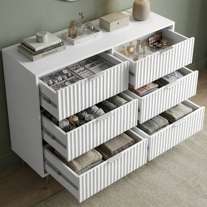 [White] chest of drawers with decorative items against a green wall placed in a natural light room