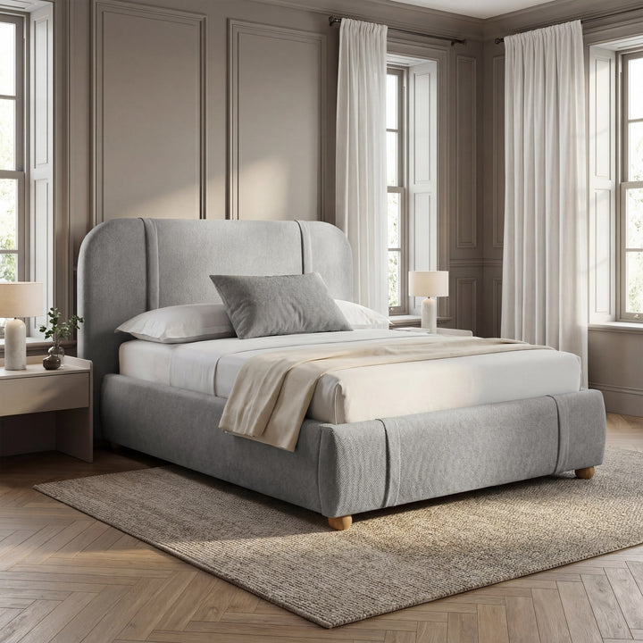 [Double | Grey] Textured fabric bed with channel-stitched curved headboard against warm moulded wall with natural daylight