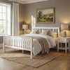 [White] Wooden double bed frame between matching nightstands and lamps with curtains and landscape art on warm wall
