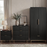 [Black] flutrina black 2 door wardrobe, 3 drawer chest and 2 drawer bedside grouped on brass legs against a panelled wall