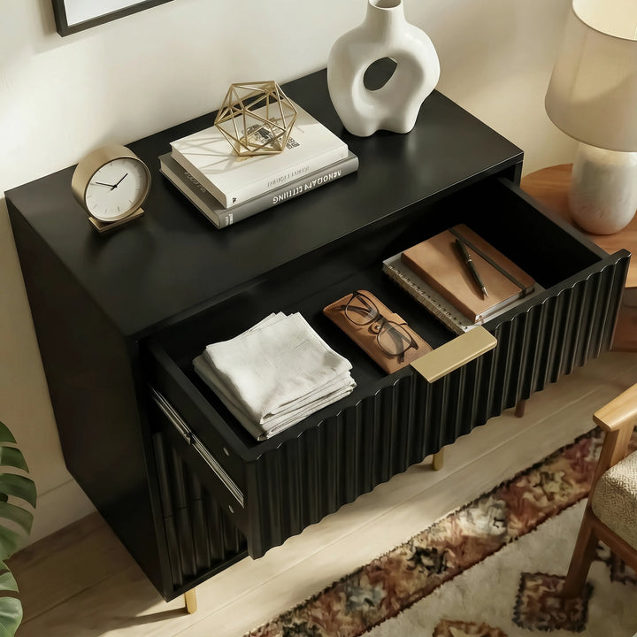 [Black] bedside table unit beside a bed, shown with an open drawer containing organised storage