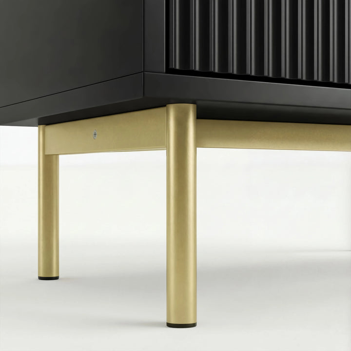 [Black] chest of drawers base close up showing slim gold metal legs and raised structurein flutrina design