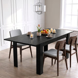 [Black Wood] Closed black wood-effect dining table styled with fruit, flowers and candles; three chairs stand around its legs.
