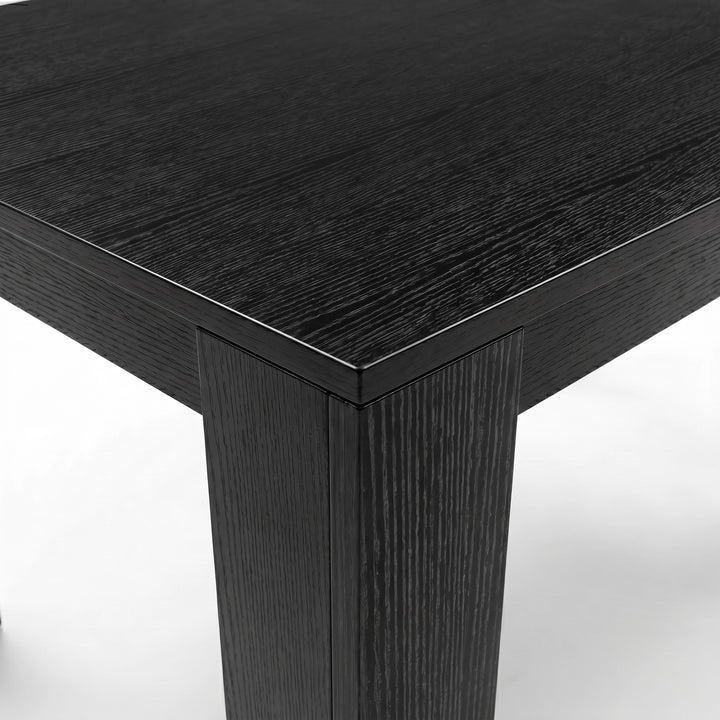 [Black Wood] Close-up of the black wood-effect tabletop corner and thick L-shaped leg; fine grain runs across the surface.