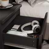 [Black] close-up of open drawer in black bedside table showing phone headphones notebook and keys