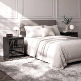 [Black] neatly made bed with white bedding and a light gray upholstered headboard, styled in a modern bedroom