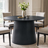 [Black] round pedestal dining table in room with slatted pedestal base and beige chairs