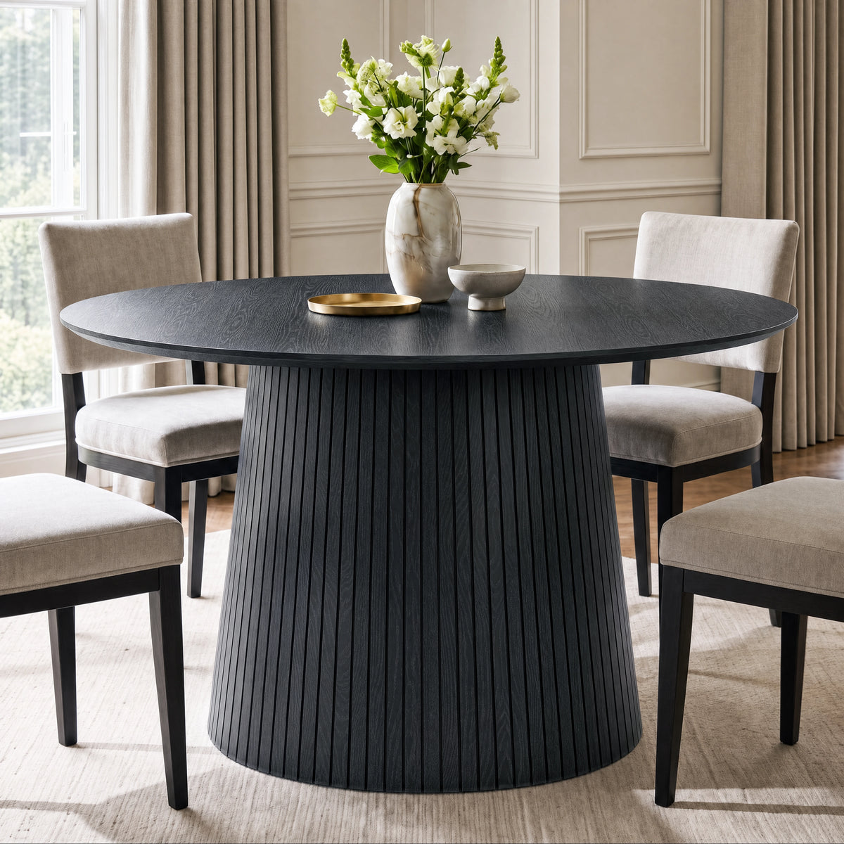 [Black] round pedestal dining table in room with slatted pedestal base and beige chairs