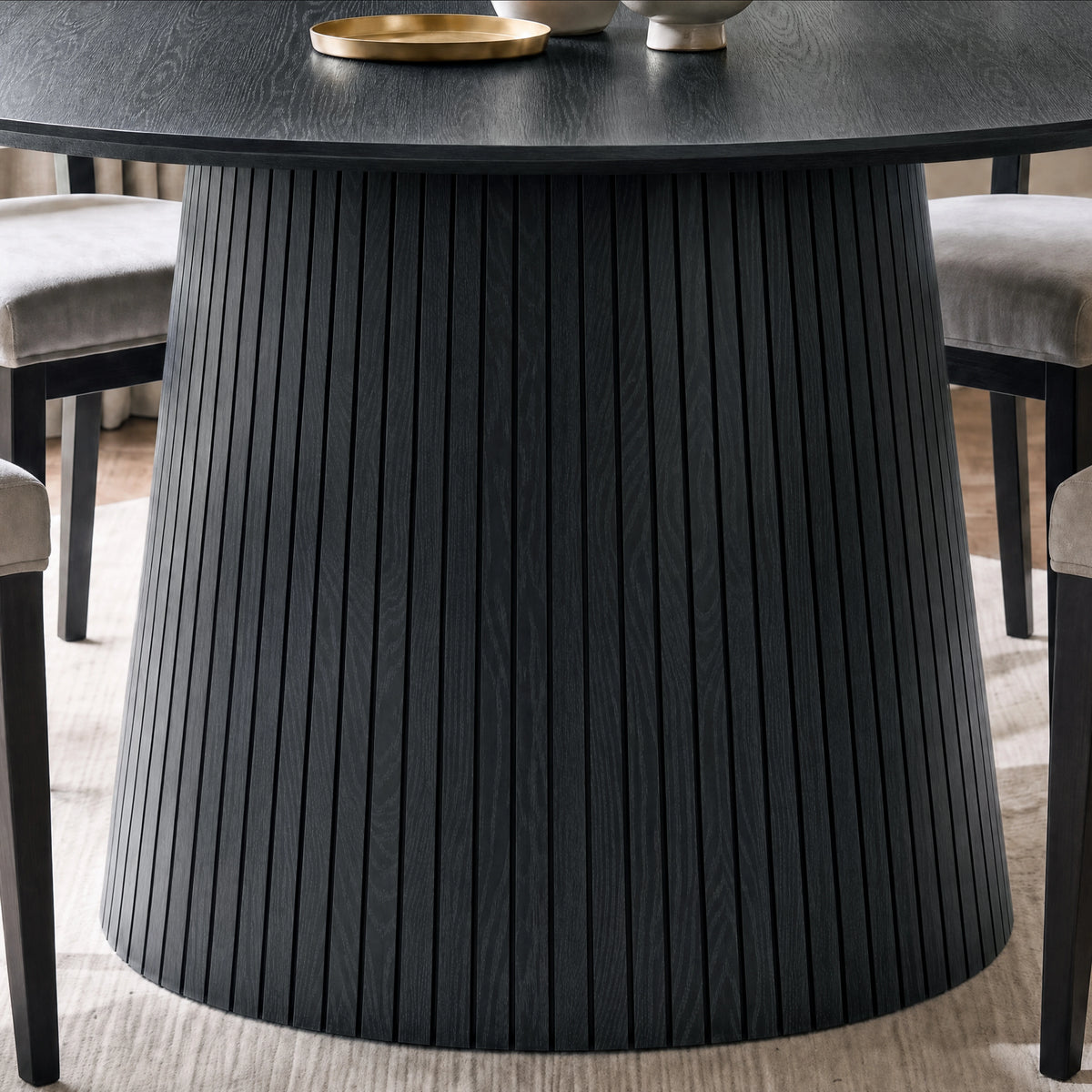 [Black] Close-up of round pedestal dining table slatted pedestal base below the table top showing slats