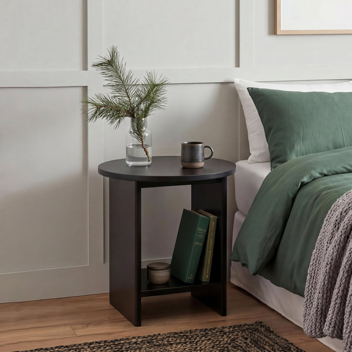 [Black] Small Round Side Table with Shelf Living Room used as bedside table beside green-dressed bed with glass vase and mug on top and books on lower shelf