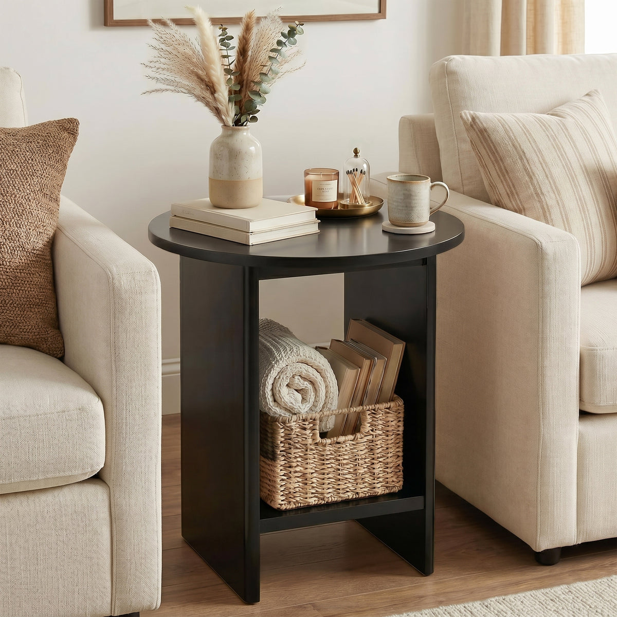 [Black] Small Round Side Table with Shelf Living Room positioned between two cream sofas with pampas vase on top and wicker basket with rolled throw on lower shelf