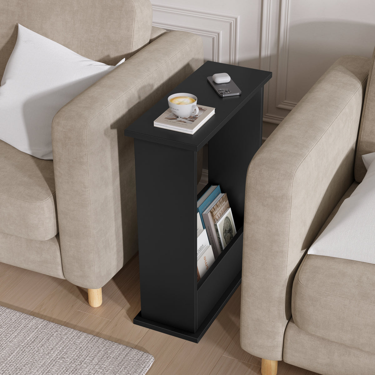 [Black] side table with a cup and books next to beige armchairs in a living room.