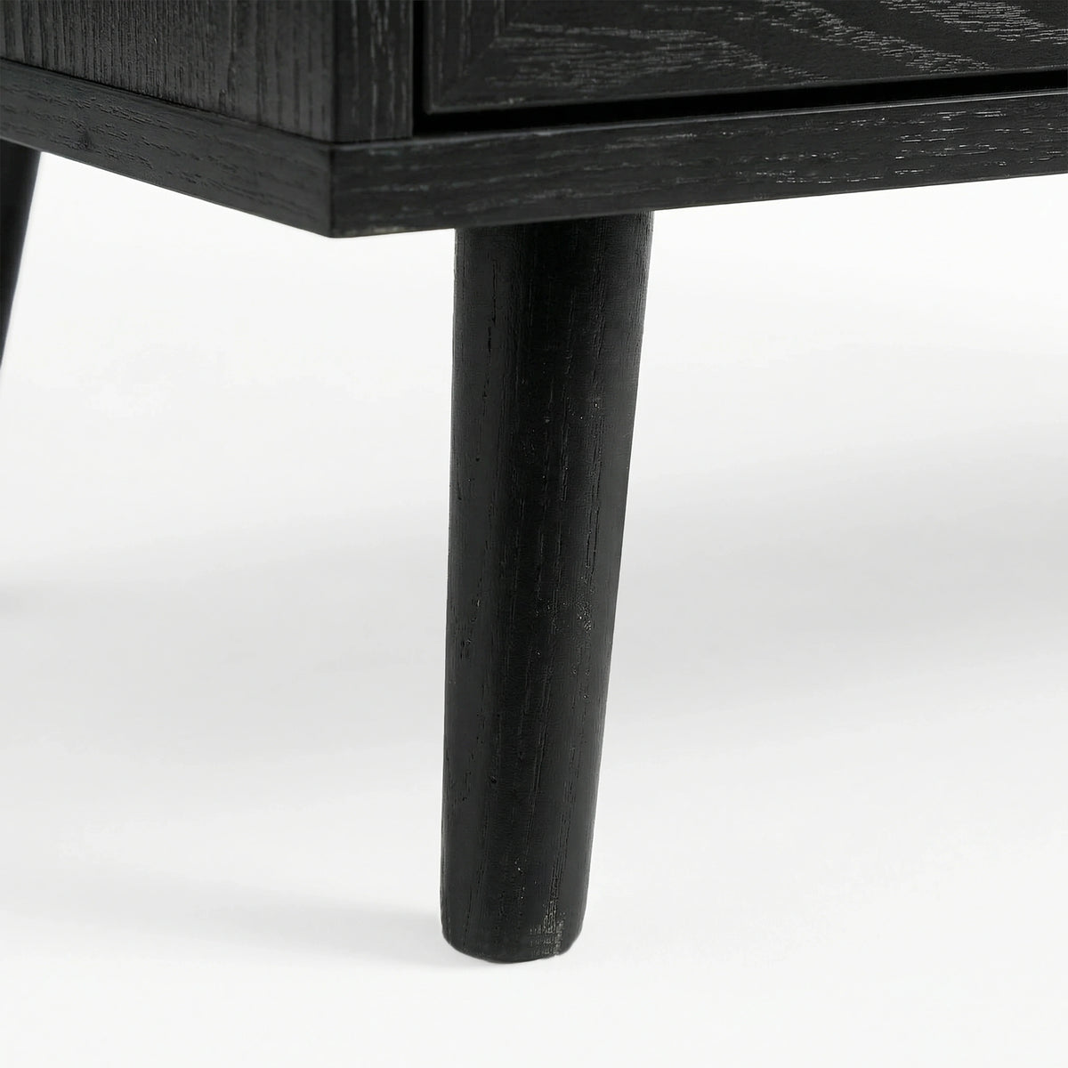 [Black] close-up of a tapered black leg on the Wovena sideboard with wood grain showing through the dark finish