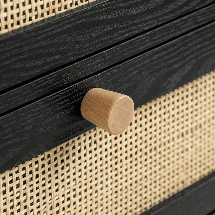 [Black] Macro detail of pine knob fitted to a black drawer rail flanked by woven rattan panels on the wardrobe