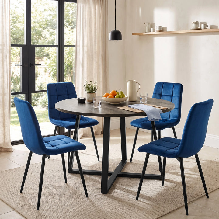 [Blue | Set of 4] Velvet dining chairs around a round wood-effect table, with tufted seats, curved backs and black legs.