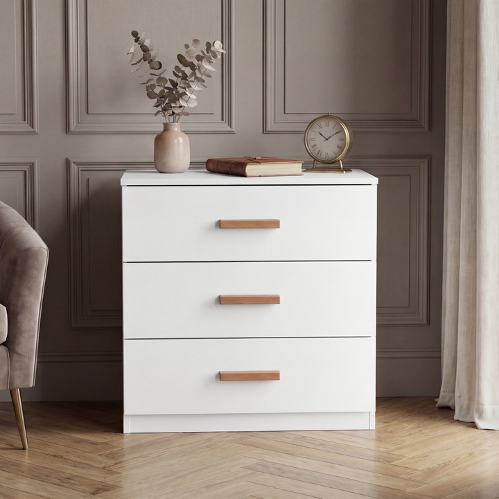 [White] Chest piece of the Blythe bedroom furniture set shown on a herringbone floor with a panelled wall behind it