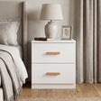 [White] Two drawer bedside table beside bed with ceramic lamp and botanical frame on top in neutral bedroom
