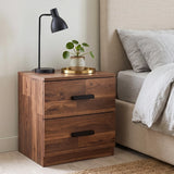 [Dark Bronx] A two-drawer wooden nightstand with a warm medium-brown finish and black handles, styled in a bedroom next to a bed with beige bedding