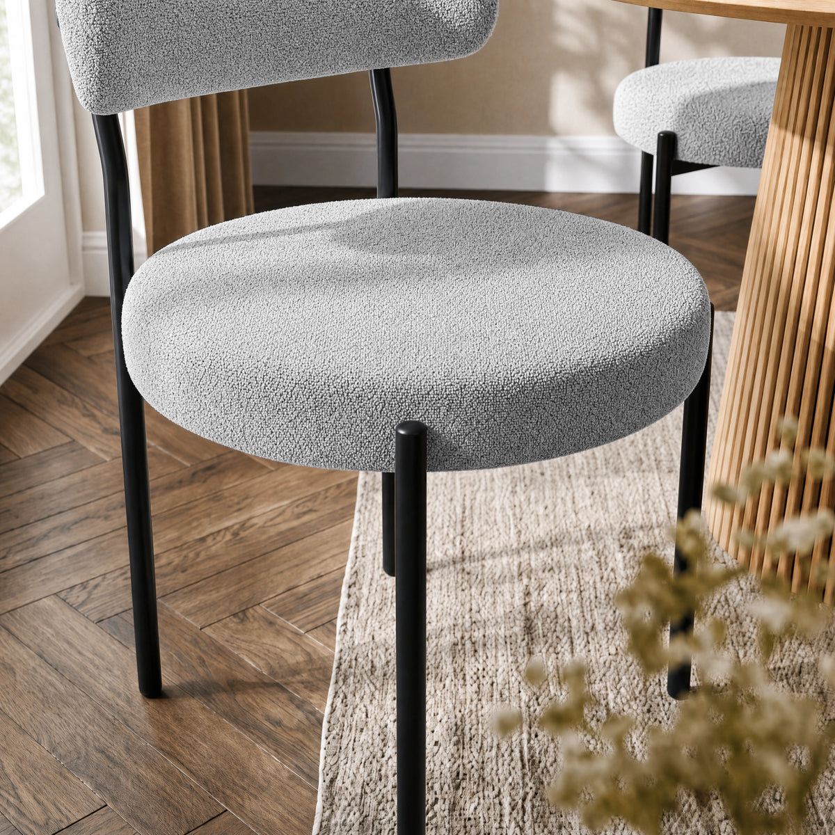 [Light Grey | Set of 4] Close-up of boucle dining chair round padded seat, curved back and black metal legs.