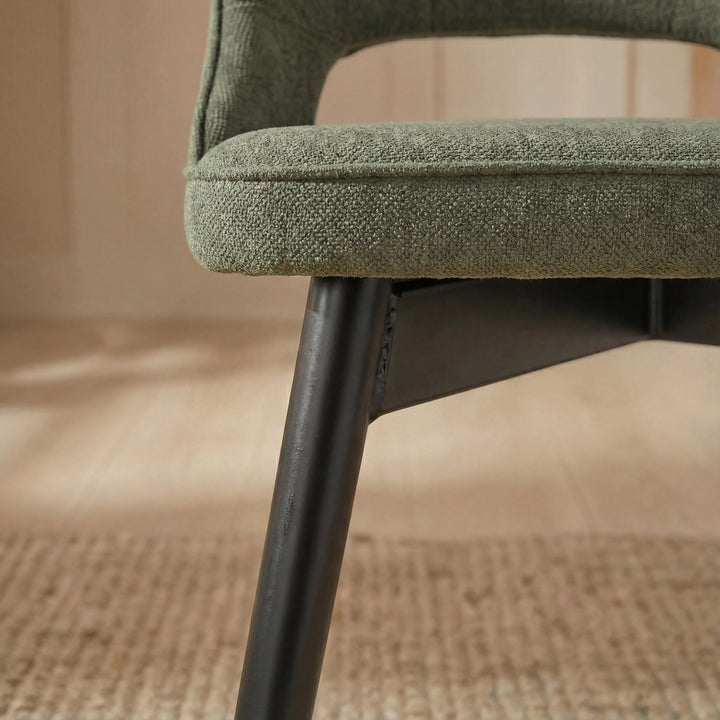 [4 Seater | Green] Tight close-up of Xylon green chair seat edge and tapered black metal leg on jute floor