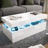 [White] high gloss storage coffee table in front of grey sofa, blue LED mid shelf holds headphones and toy car