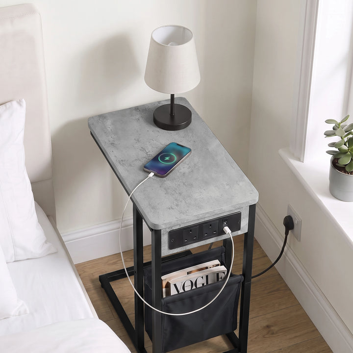 [Concrete] Top view of C-shaped side table with concrete-effect top, charging cable, phone and pouch used as bed side table