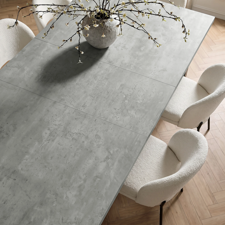 [140cm | Concrete] Top-angle view of tabletop panels with rounded vase, stems, cream chairs, and wooden floor