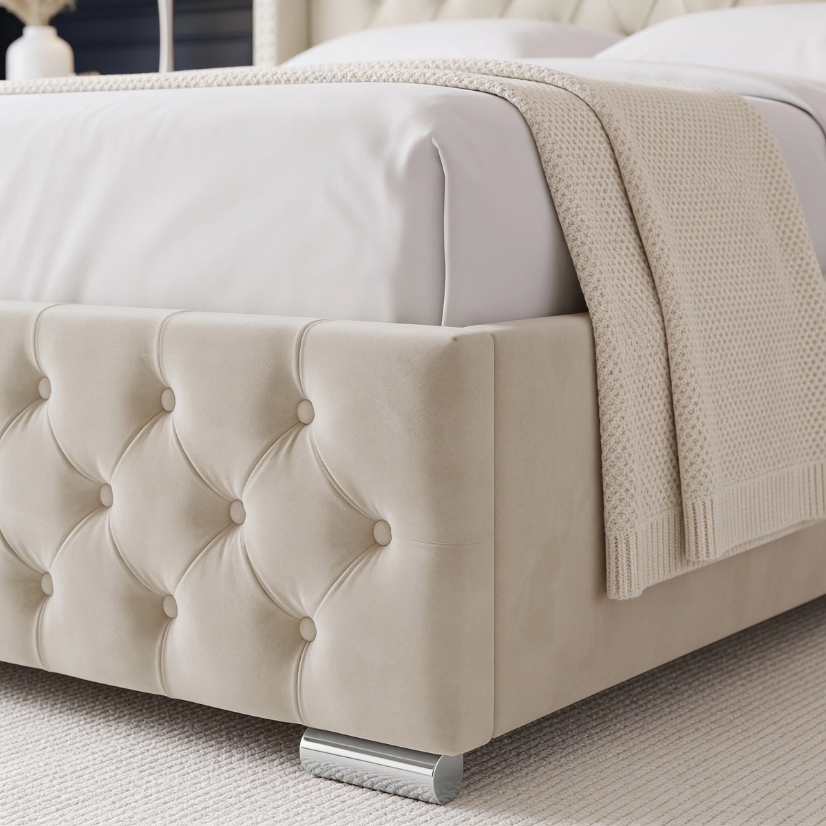 [King | Beige] close-up of a tufted upholstered bed frame in a warm cream or beige fabric, shown with white bedding and a textured cream throw blanket.