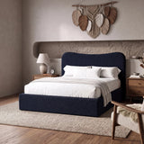 [Double | Blue] upholstered bed with a high curved headboard in a modern bedroom with a textured wall, and a leaf wall hanging.
