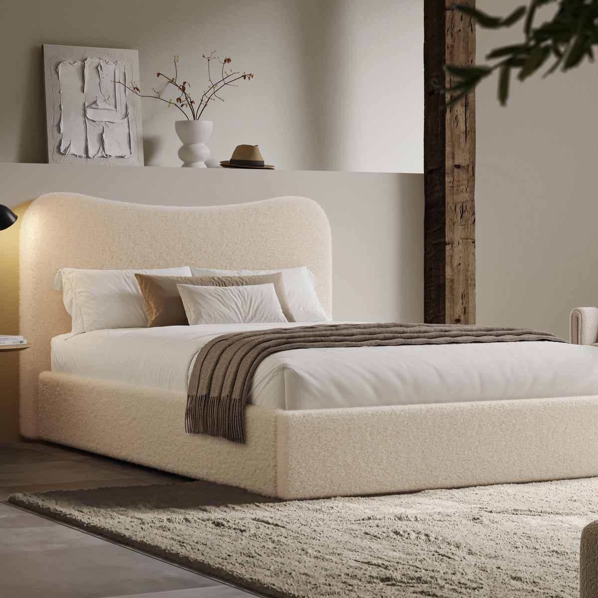 [Double | Beige] Boucle fabric ottoman bed from the side with white bedding and fringed throw beside floating shelf with art