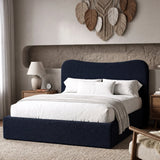 [Double | Blue] Boucle fabric ottoman bed from the side with white bedding and fringed throw beside floating shelf with art