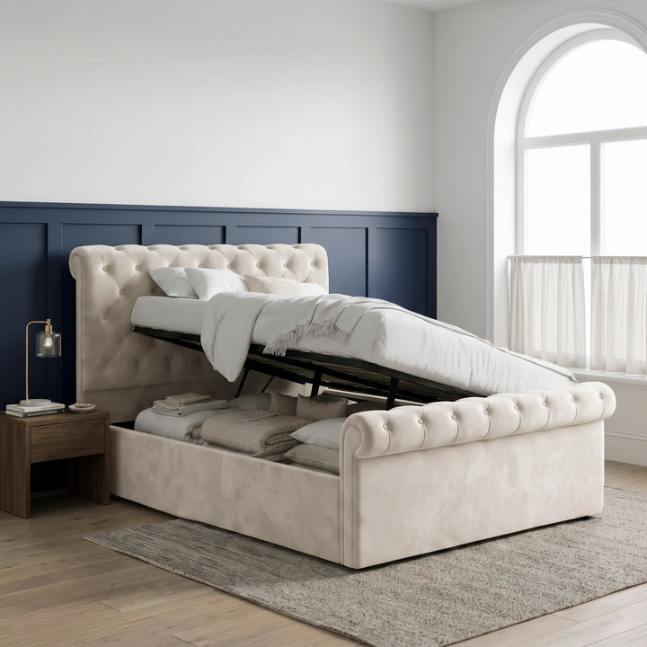 [Double | Beige] Side-lift storage view with raised mattress base, black frame, folded bedding, pillows, and arched window