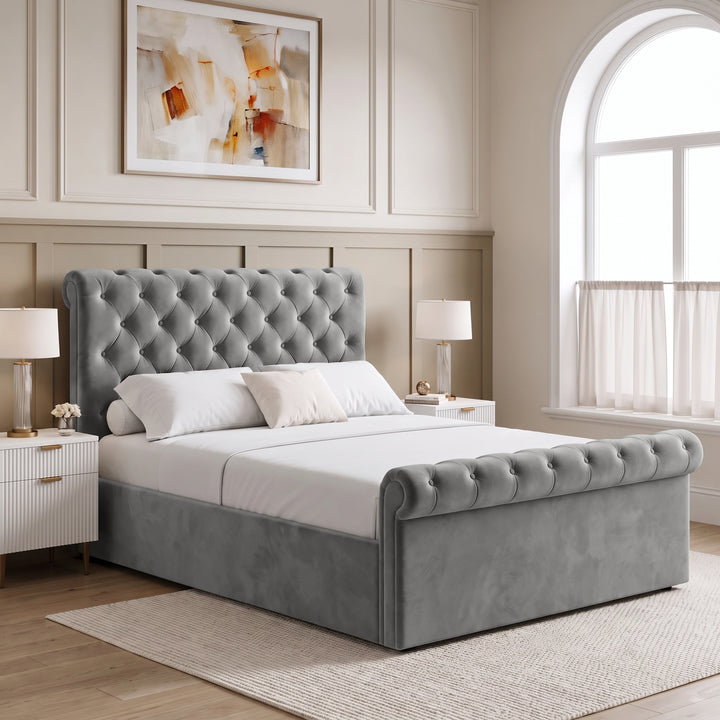 [Double | Grey] Angled bedroom view with tufted headboard, rolled footboard, twin bedside lamps, wall art, and window