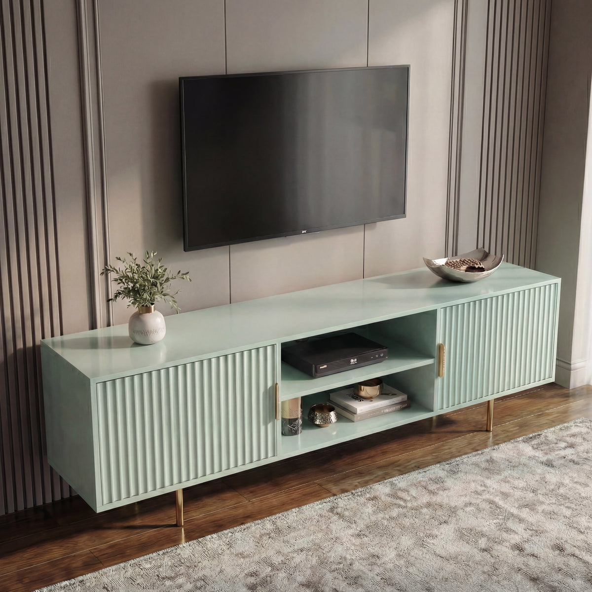 [Sage Green] Wide-angle sage green 180cm TV unit lifestyle, TV mounted, vase of green foliage on top left, brass legs on rug.