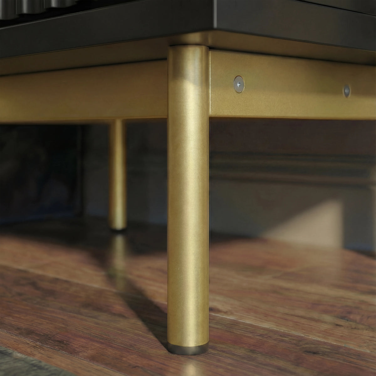 [Black] bedside cabinet lower corner with raised golden metal legs and structured base placed on a wooden flooring