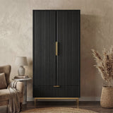 [Black] freestanding wardrobe in flutrina design with gold handles and legs placed in a natural light room