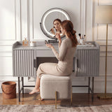 [Grey] side-profile lifestyle of the grey fluted vanity with a person at the white-lit round mirror and beige stool