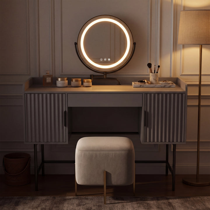 [Grey] side-profile lifestyle of the grey fluted vanity with a person at the white-lit round mirror and beige stool