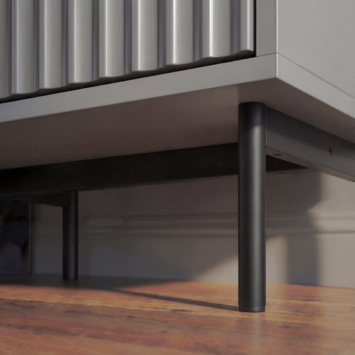[Grey] bedside table bottom corner showing slim black metal legs and raised support placed in a natural lighting