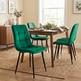 [Green] Velvet dining chair in front of a table, with a curved tufted back, black legs and matching chairs behind.