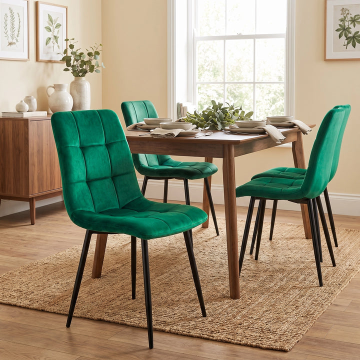 [Green] Velvet dining chair in front of a table, with a curved tufted back, black legs and matching chairs behind.