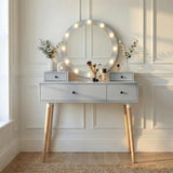 [Grey] Dressing Table With Drawers shown front-on with lit Hollywood mirror, eucalyptus stems, perfume bottles, and brushes in sunlit panelled space