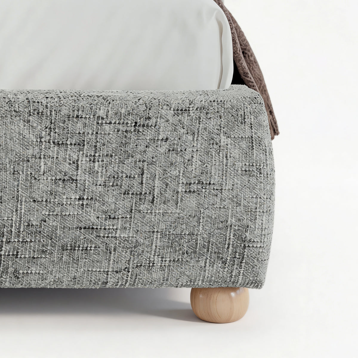[King | Grey] Embracea bed base close-up showing curved footboard profile, woven fabric texture, and solid oak round leg