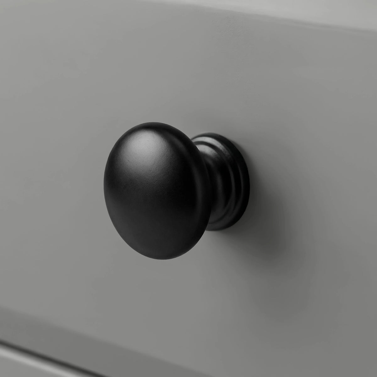 [Grey] Haven close detail of black round knob on smooth drawer front with softly bevelled panel edge