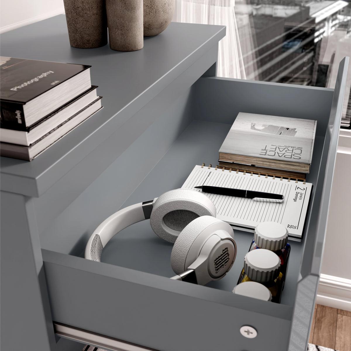[Grey] Close-up of drawer in grey high gloss chest, displaying storage for headphones, books, and personal items.