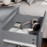 [Grey] close-up of open drawer in grey bedside table showing phone headphones notebook and keys